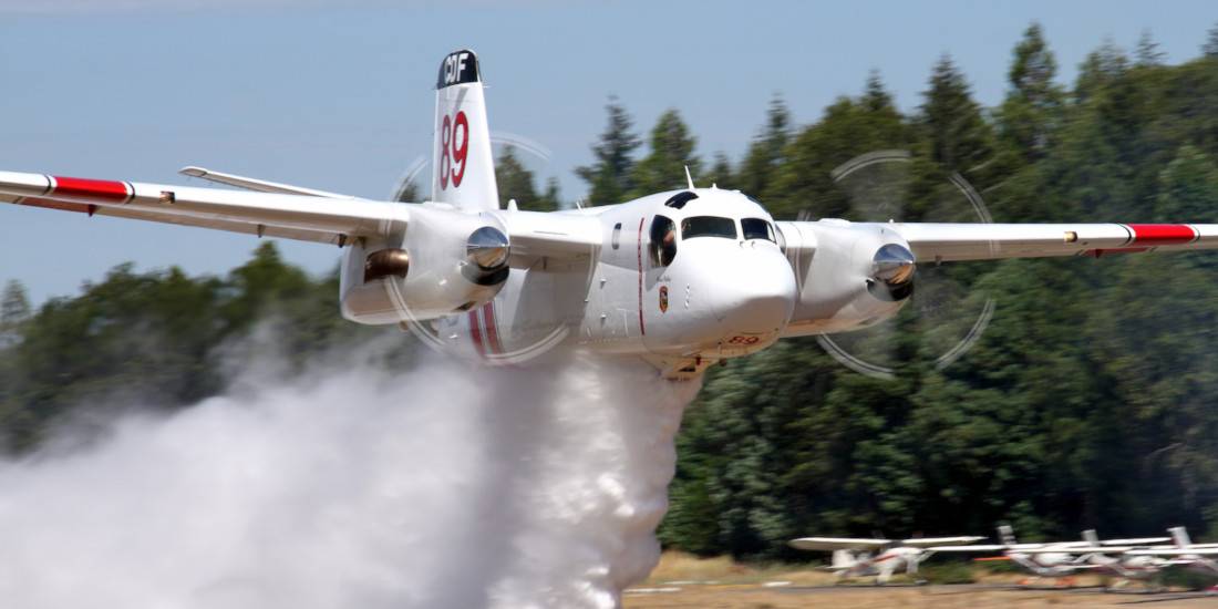 Air tanker releasing fire retardant low over a forest