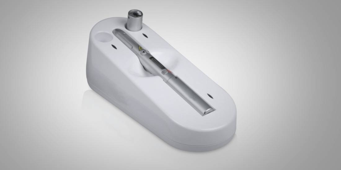 Medical laser handpiece resting in its white stand